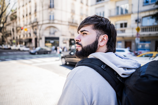 Traveler young man walking and looking away in the street