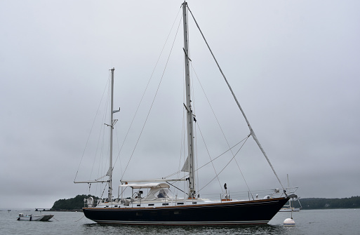 Gray day with a large luxury sailboat anchored in a Maine harbor.
