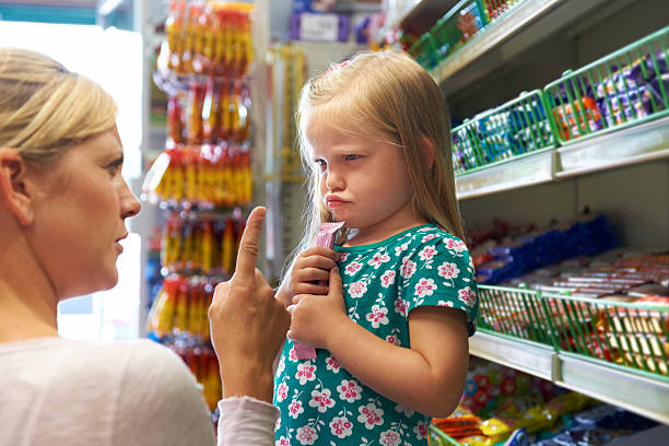 kind mit arguement mit mutter auf candy bar - familie mit einem kind stock-fotos und bilder