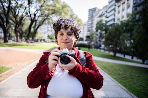 Portrait of a mid adult woman holding a photographic camera in the park