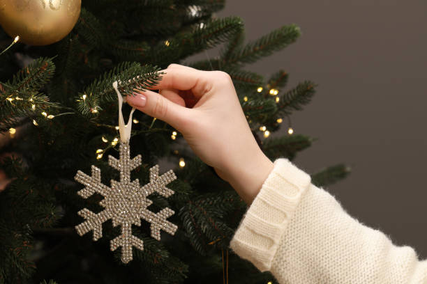 istock Woman decorating Christmas tree with beautiful bauble on grey background, closeup 1791693334