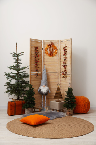 Beautiful Christmas themed photo zone with trees, dwarf and decor near white wall