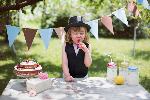 Cute little boy with party whistle celebrating birthday party.