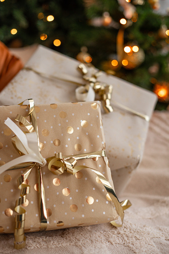 Christmas presents with gold wrapping paper and ribbons under Christmas tree