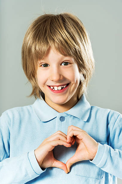 Portrait of a smiling boy. Portrait of a smiling, little boy showing heart shape. cute boy show love symbol hand stock pictures, royalty-free photos & images