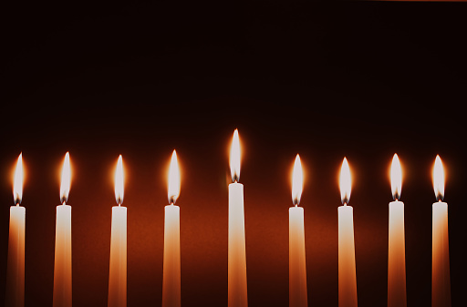 Hanukkah candles. Traditional candelabrum with burning candles on black background. Celebrating a religious Jewish holiday.
