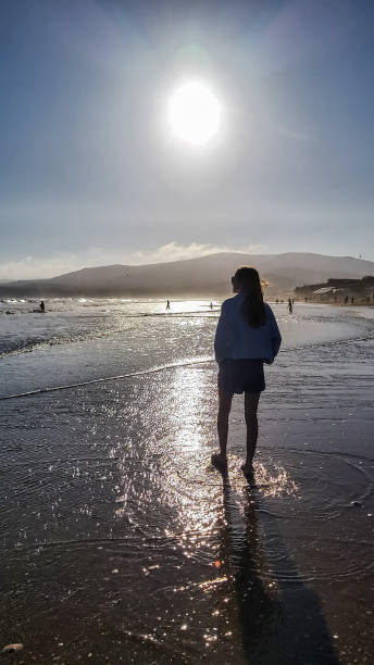 istock A girl walks along the sandy beach in summer during sunset. 1791782376