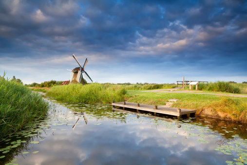 windmill on riverside with reflected blue sky