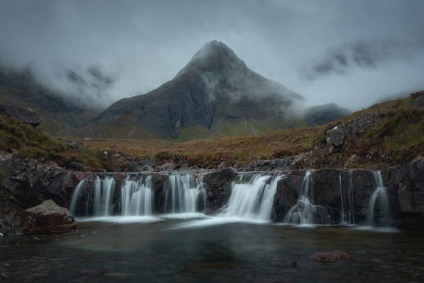 Morning view of a river with a waterfall and a cloud-shrouded mountain peak stock photo