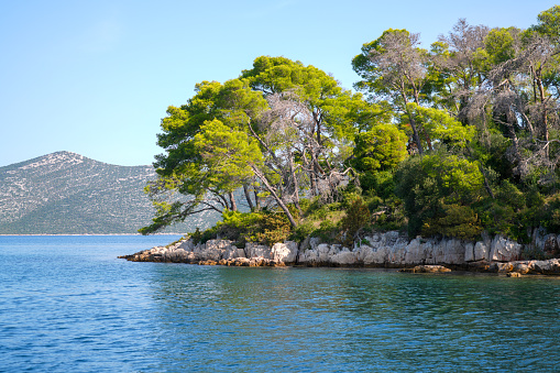 View from sailing boat at blue sea, blue sky and green islands around as sailing tranquility on Adriatic sea in Croatia.  It is central Dalmatia coast not far from big Town Zadar on Croatian mainland.  Adriatic Sea as part of Mediterranean.
