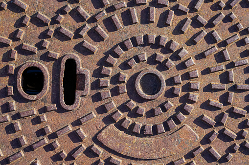 View of a rusty brown manhole cover under bright light