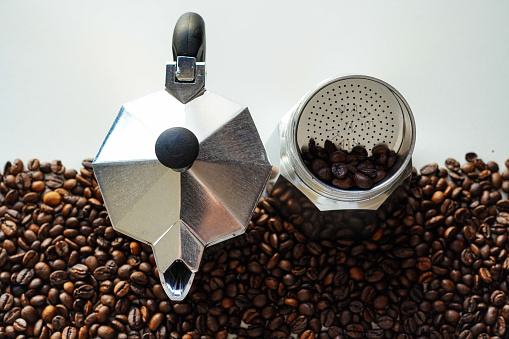 Italian mocha pot (Caffettiera or macchinetta del caffè), Italian coffee maker with coffee beans in the background