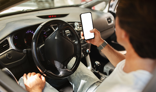 Man driver sitting in front sit in the car, holding mobile phone with white blank screen, map gps navigation, unrecognizable guy checking location destination, using app, travelling alone by auto