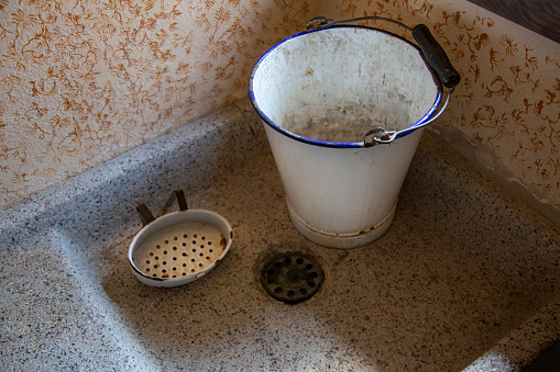 Vintage metal bucket and soap dish in an old stone kitchen sink bowl