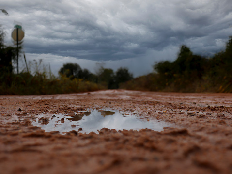 Country road made of Georgia clay with puddles that have reflections of the stormy clouds