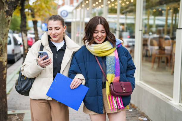 istock Two university students walking on the road and looking at mobile phones 1791863132