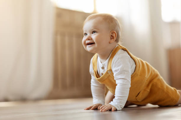 adorable blonde infant baby crawling by home, copy space - bebeklik stok fotoğraflar ve resimler