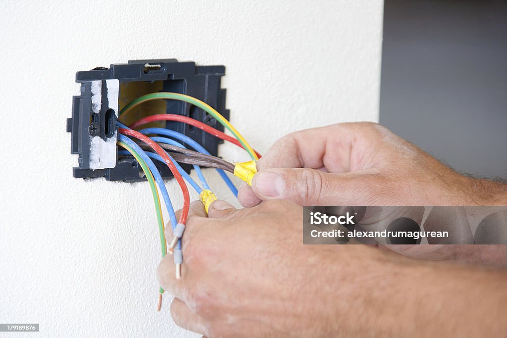 Installing power outlet Electrician preparing cables for outlet connection Bib Overalls Stock Photo