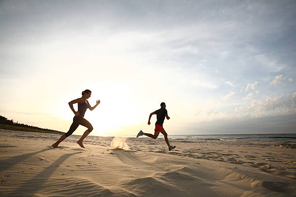 istock Man and women running on beach at sunset 179190382
