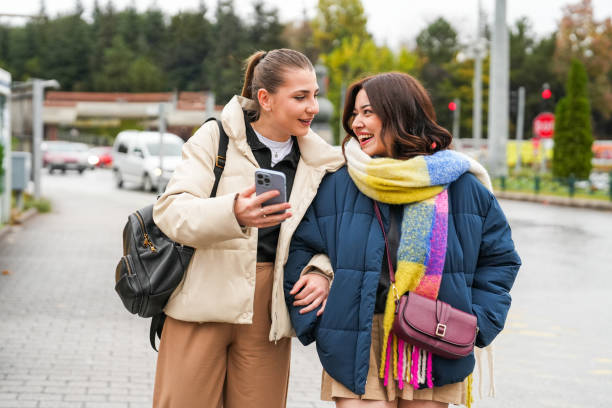 istock Two university students walking on the road and looking at mobile phones 1791916543
