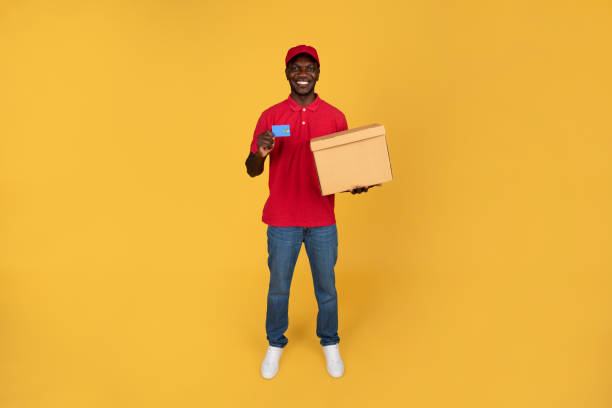 istock Smiling millennial black guy courier hold box, recommends credit card for pay 1791920230