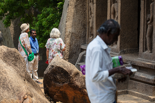 Mahabalipuram, India - October 3, 2023. Two mature women receive information from a guide at a historic site in Tamil Nadu.