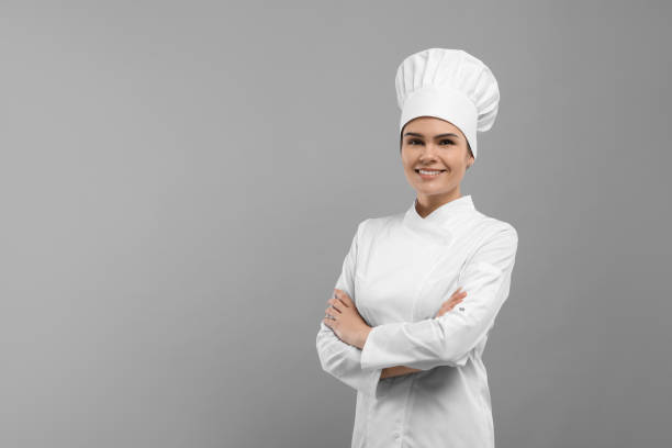 istock Happy female chef wearing uniform and cap on light grey background. Space for text 1791946186