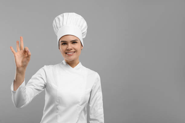 istock Happy female chef wearing uniform and cap showing ok gesture on light grey background. Space for text 1791946683