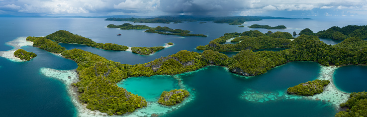 Rain clouds slowly approach the incredible islands of Pef in Raja Ampat, Indonesia. These stunning islands are fringed by mangrove trees and surrounded by beautiful coral reefs.
