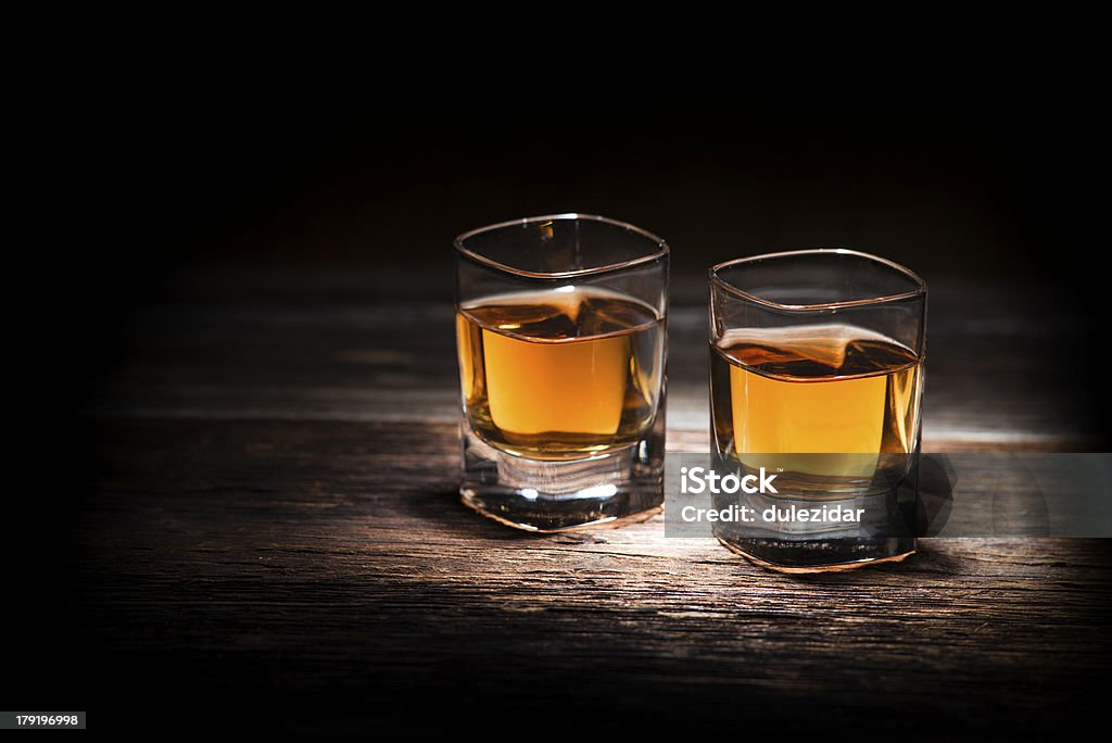 Zbliżenie z dwie szklanki whisky na drewniany stół - Zbiór zdjęć royalty-free (Kieliszek do wódki)