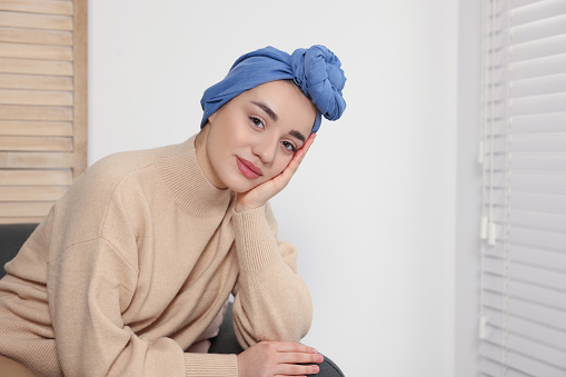 Cancer patient. Young woman with headscarf near window indoors, space for text