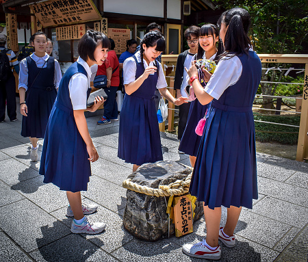 Kyoto, Kyoto prefecture / Japan - 05 12 2018: Japanese school girls in uniform visit Kiyomizu-dera in Kyoto, guiding each other to walk blindly between two stones to find true love at Jishu Shrine.