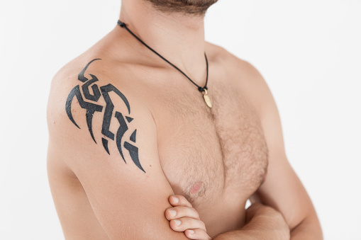Tattoo artist tattooing a man's back in his tattoo studio.