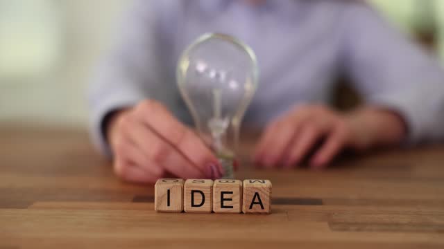 Businesswoman touches light bulb and word idea