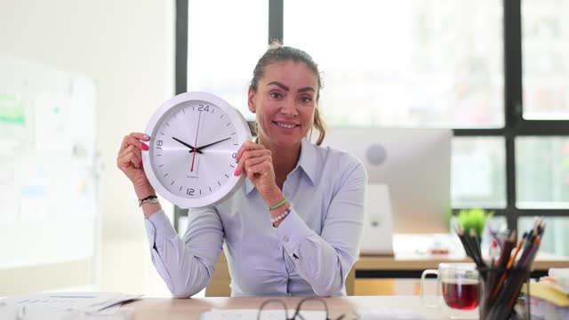 Woman with a large round wall clock in office
