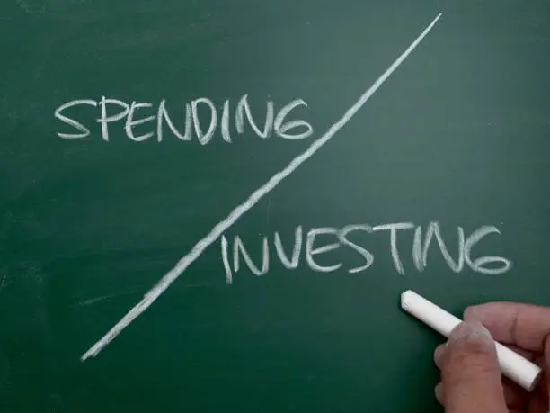 Photo of Spending or investing, word text written on chalkboard, business quotes