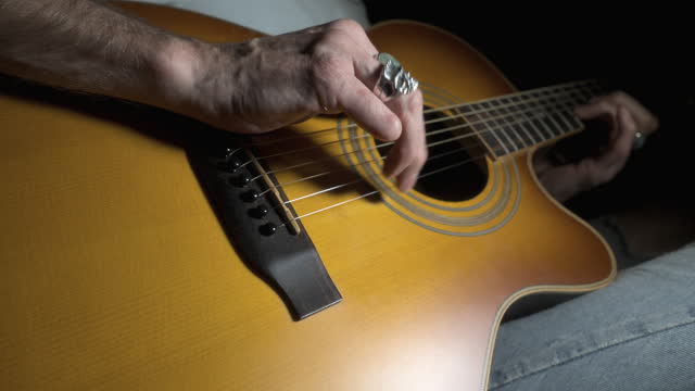 Amputee playing acoustic guitar with close up on missing finger. Quarter stop pro mist filter. 60fps.