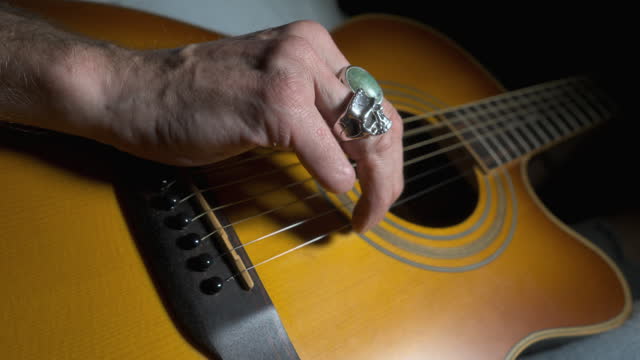 Amputee playing acoustic guitar with crop in to missing fingers. Quarter stop pro mist filter. 60fps.