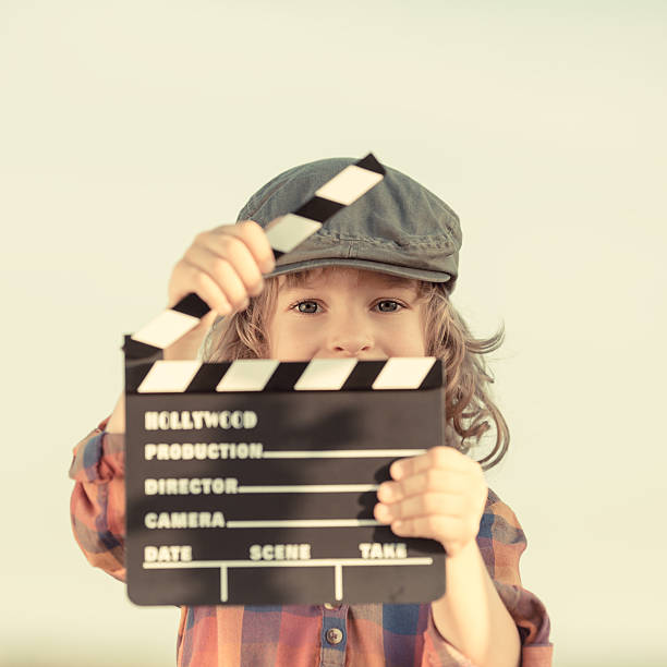 Kid holding clapper board in hands stock photo
