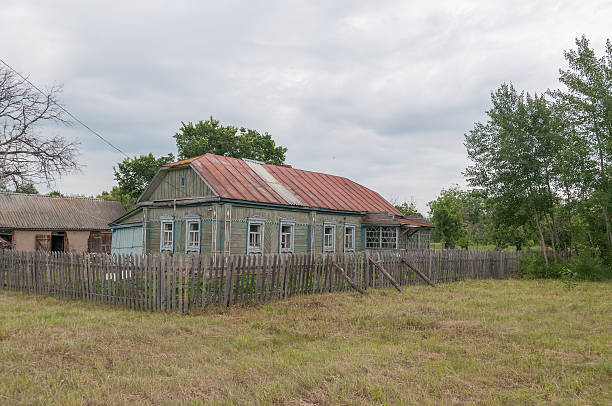 istock Old wooden house behind picket against cloudy sky background 179211734