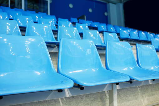 No people on blue plastic chairs of empty tribune at spacious modern stadium for fans of various sports matches, competitions and games