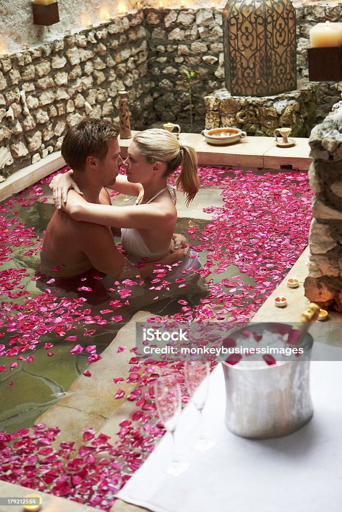 Пара расслабляющий в цветок лепестки крытый бассейн в спа-центре - Стоковые фото 20-29 лет роялти-фри