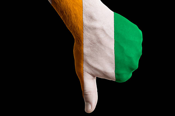 Hand with thumb down gesture in colored ivory coast national flag as symbol of negative political, cultural, social management of country
