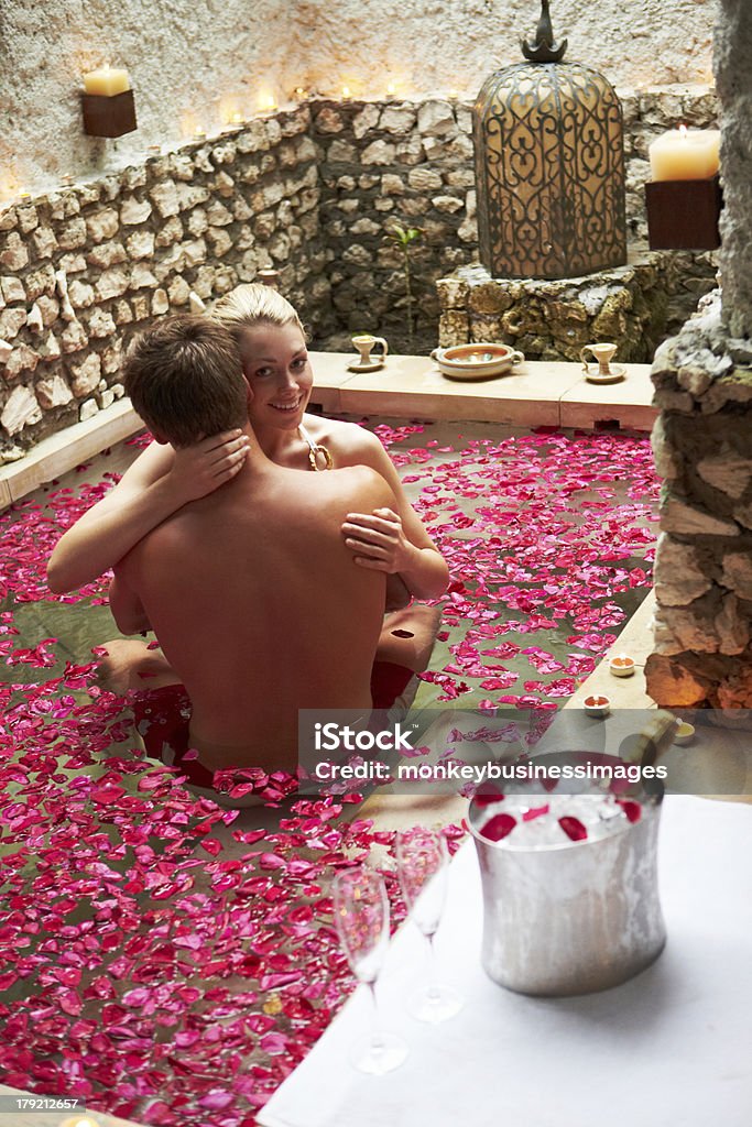 Pareja relajándose en flor pétalos en la piscina bajo techo del Spa - Foto de stock de Parejas libre de derechos