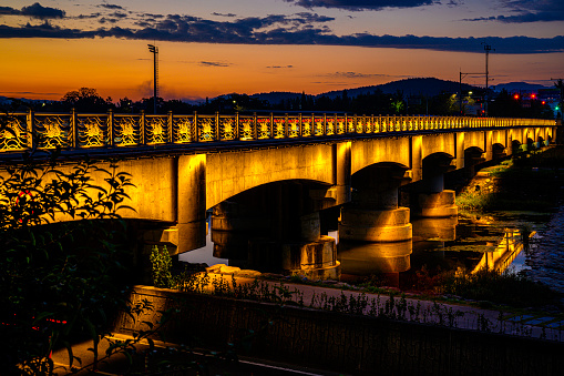 Gyeongju City Sunrise Landscape and dramatic cloudscape at dawn with the view of Seochungyo Bridge over Nam Chon or South River, illuminated by the golden lights, in South Korea