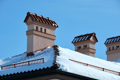 Closeup of house roof top covered with snow in cold winter. Tiled covering of building in wintertime weather.