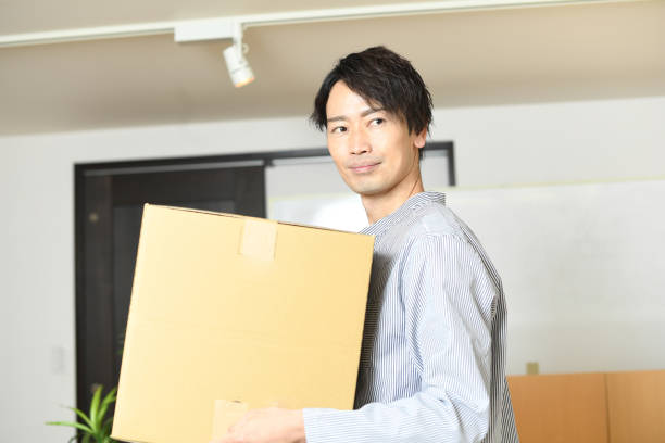 istock Young Asian man smiling and carrying cardboard at home 1792146818