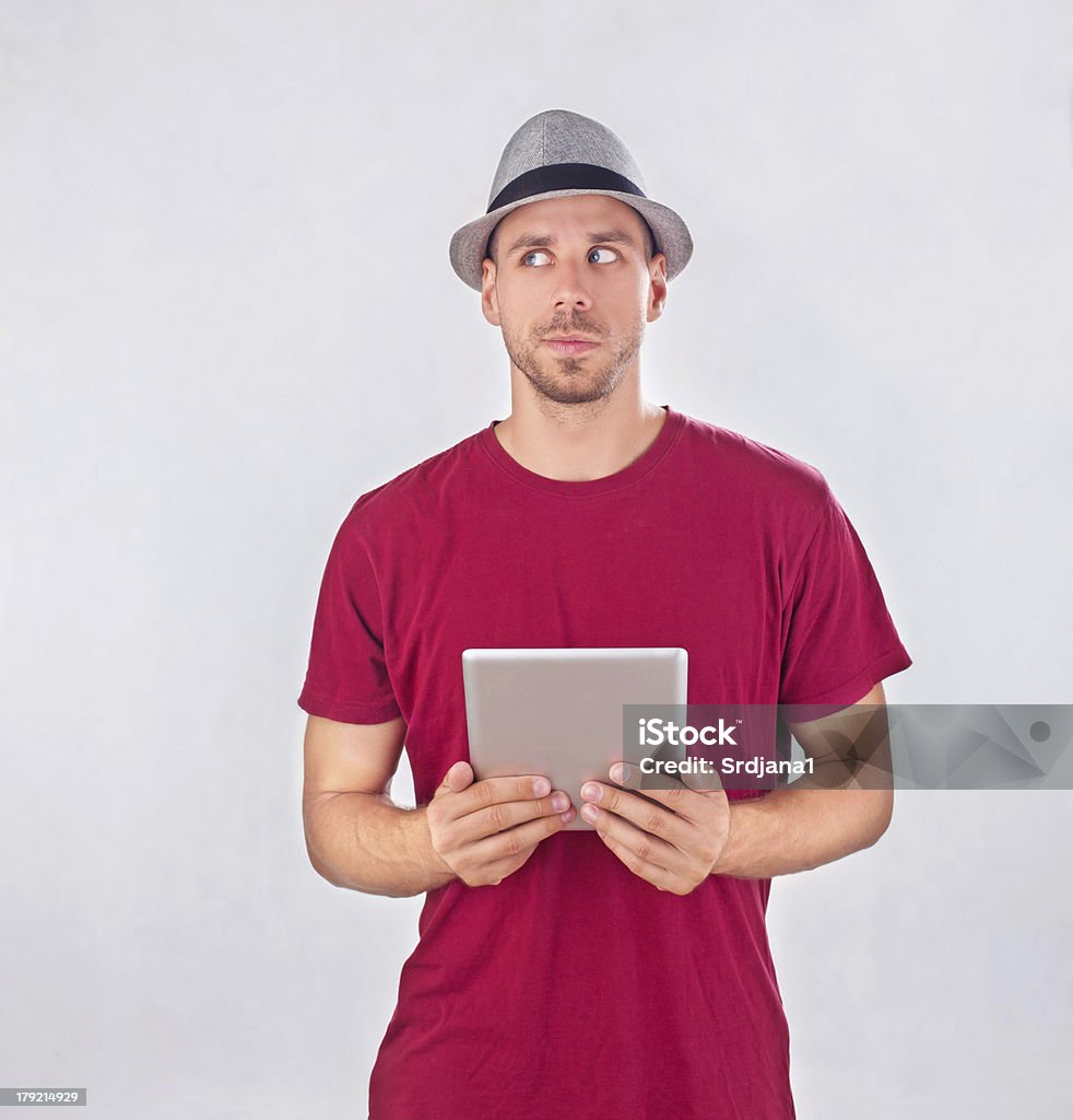 Frowned uomo confusedly lookingat lo spazio copia, tenendo un tablet PC - Foto stock royalty-free di Scaricare dall'internet