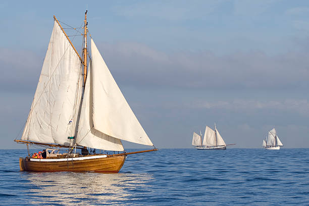 Tender with white sails Three ships with white sails in the calm sea gaff sails stock pictures, royalty-free photos & images