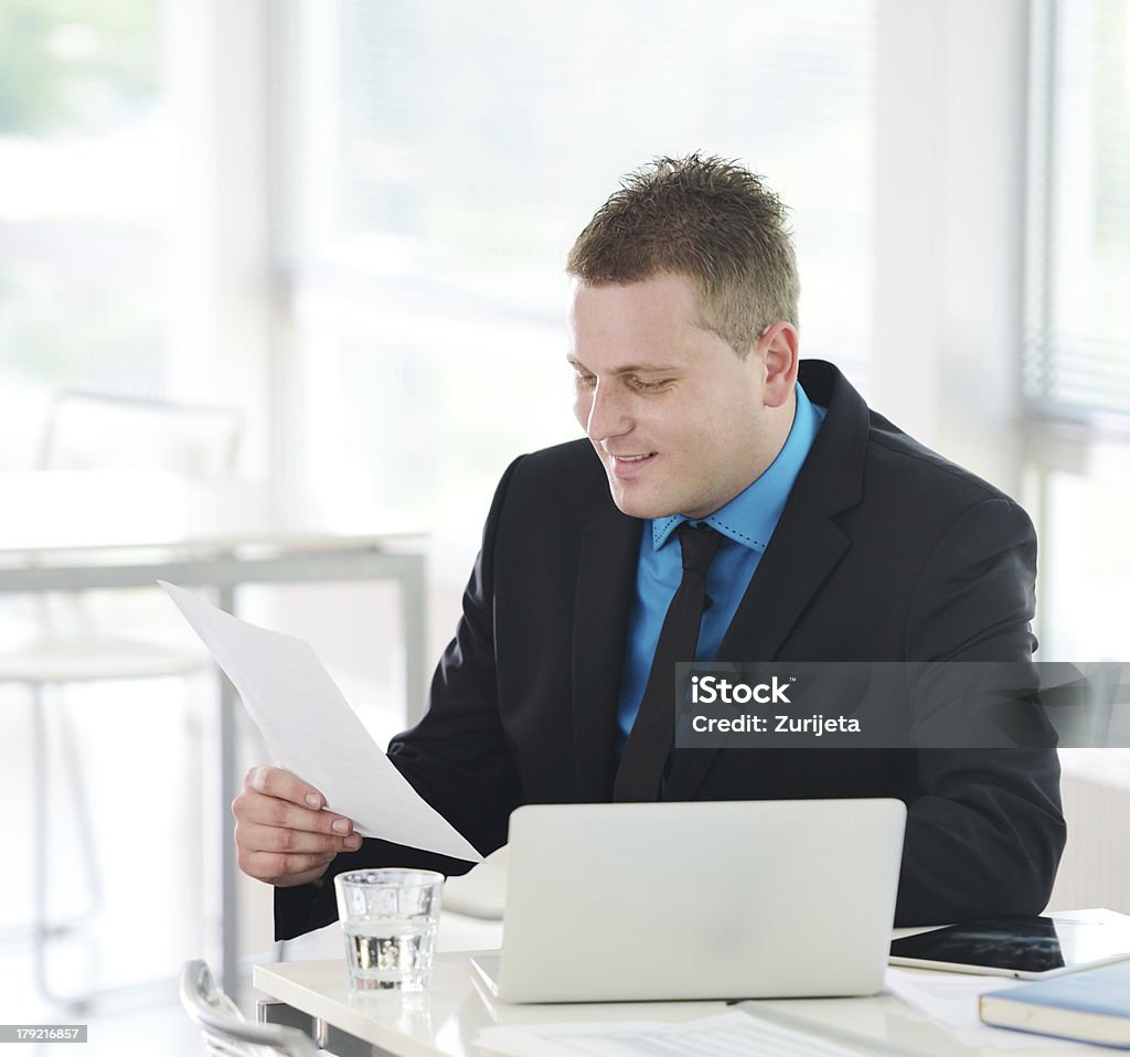 Descontraído executivo sentado na mesa de escritório leitura do relatório - Foto de stock de Adulto royalty-free